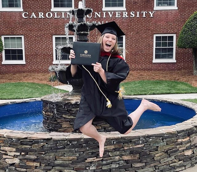 Girl jumping in cap and gown on campus